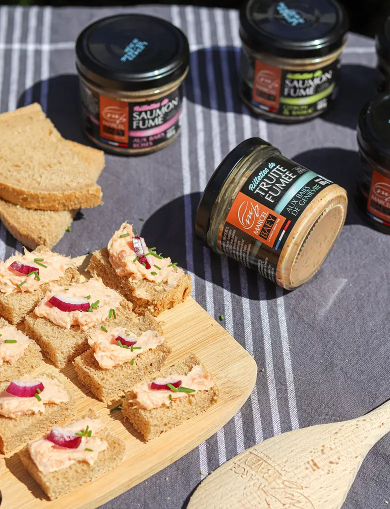 Toasts de rillettes de saumon fumé et pots de rillettes sur une nappe rayée